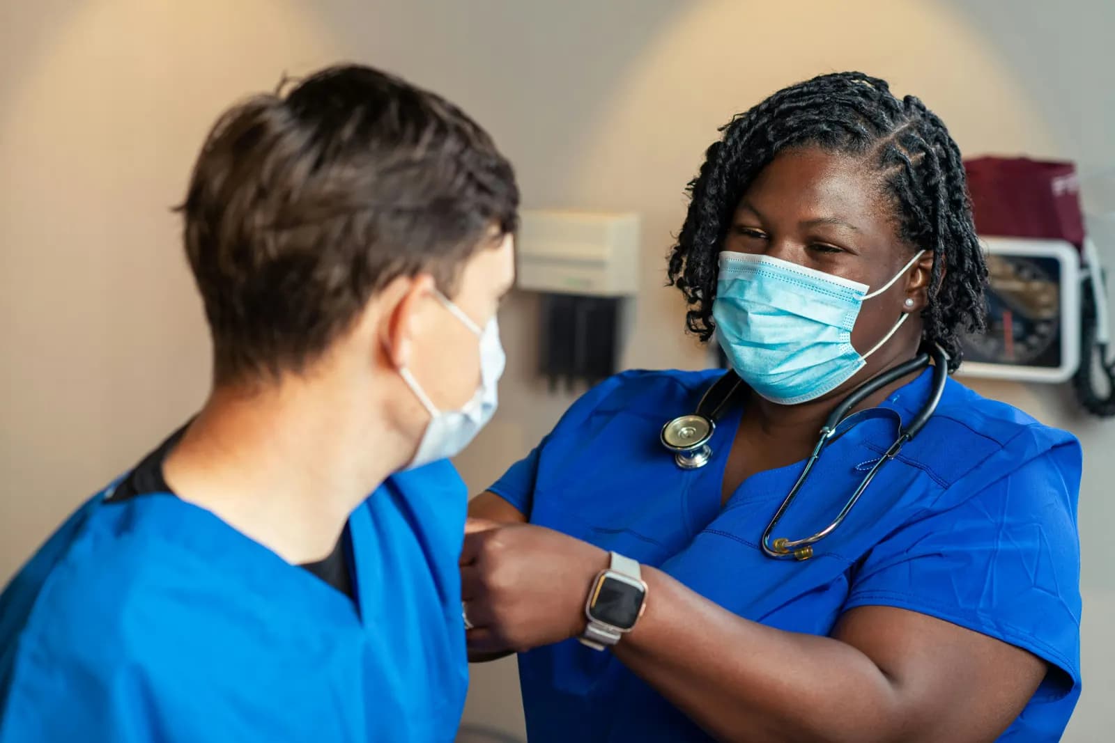Nurse with a stethoscope talking with someone in an exam room
